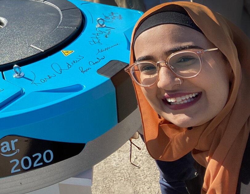 A woman poses with an Amazon Robotics unit.