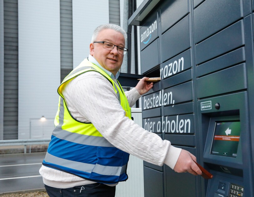 Ein Mann in Sicherheitsweste vor einem Amazon Locker
