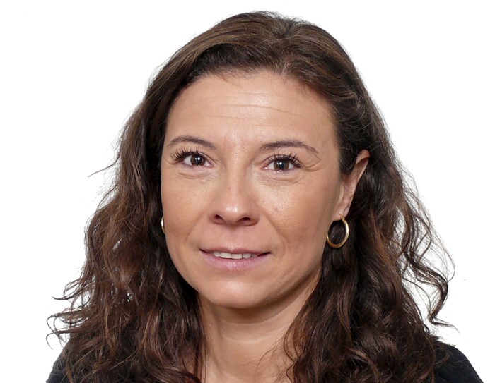 Carmen María Martínez Martínez-Burbana, responsable de Relaciones Laborales. Mirando a cámara con el pelo largo, castaño y ondulado. Con pendientes, sonriente y camisa gris. LLeva un jersy de punto negro con volantes en los hombros.