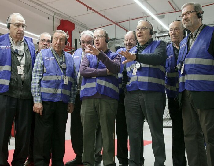 Un grupo de ingenieros jubilados durante una visita al centro logístico. Todos ellos visten con chaleco azul.