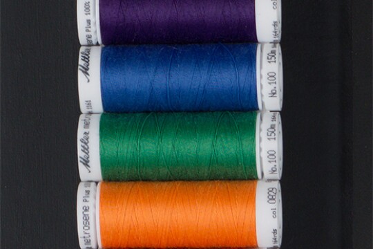 Spools of thread in a range of colors: gray, purple, blue, green, orange, and red.