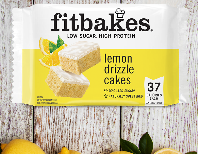 An image of a lemon flavoured Fitbakes on a wooden table with lemons at the bottom.