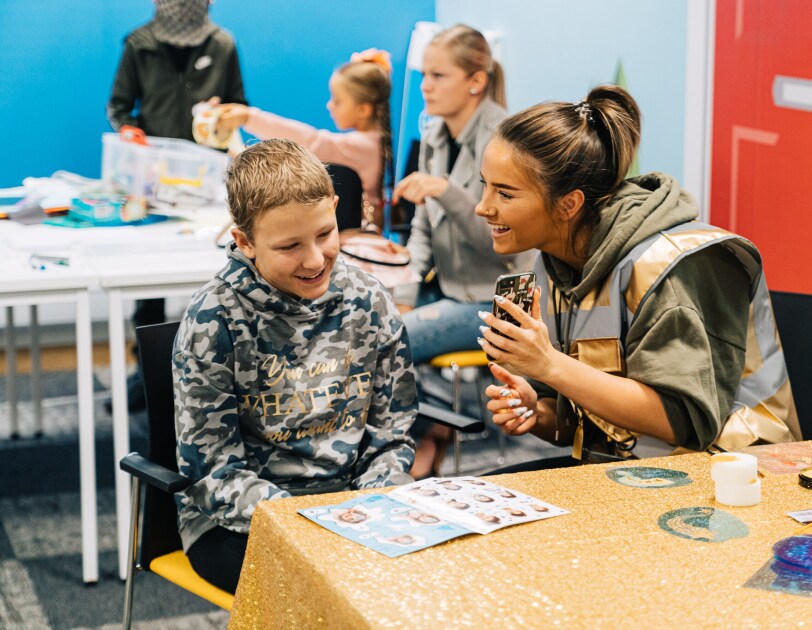 A child and an Amazon employee smiling and playing together at a STEM camp