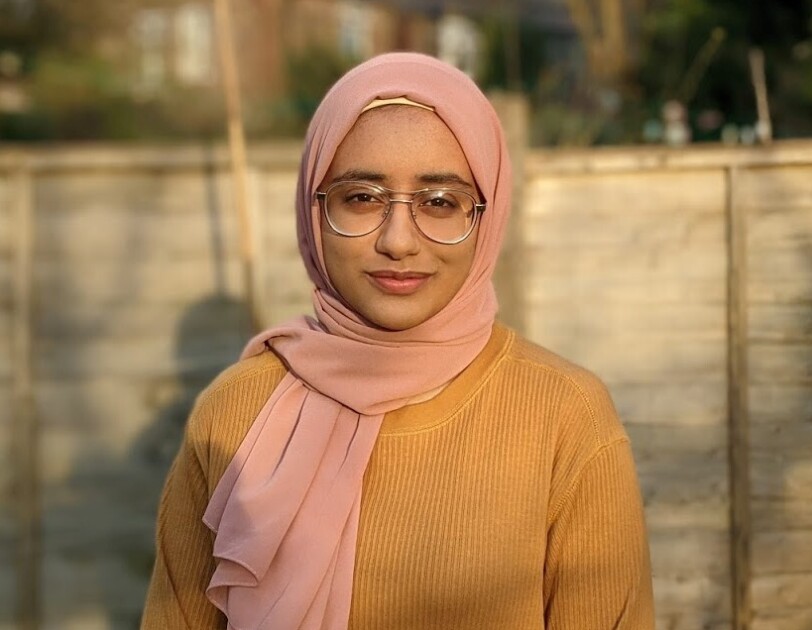 Zoya Anwar standing in a garden in front of a fence