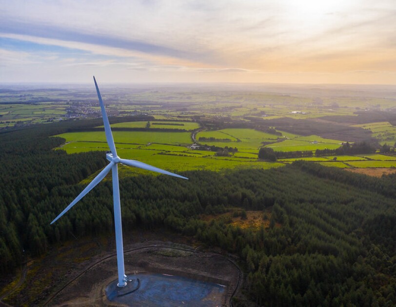 A wind turbine, from an Amazon wind farm, in front of fields in Europe.
