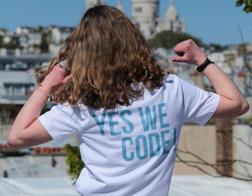Une jeune fille montre son t-shirt sur lequel "Yes We Code" est inscrit