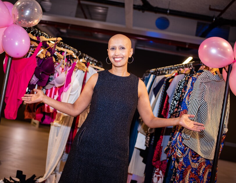 Amazon Fashion Studio employee Balvinder Pawar smiling in front of several racks of clothes decorated with pink balloons at a charity sample sale.
