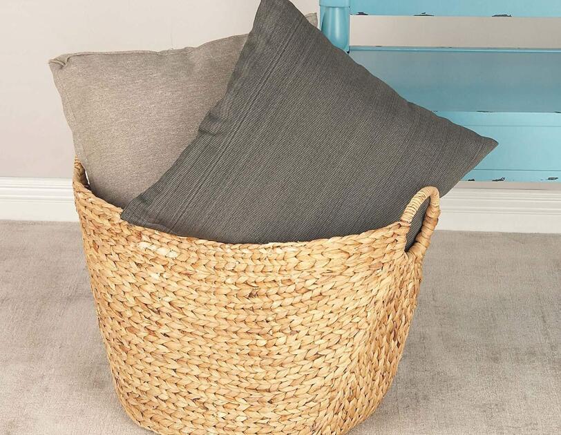 Two cushions in a woven grass basket, in front of an aqua bench.