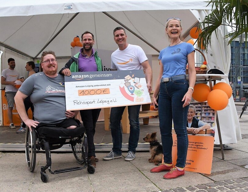 Vier Personen halten einen Spendenscheck. Links im Bild ist Marco Pratsch im Rollstuhl zu sehen