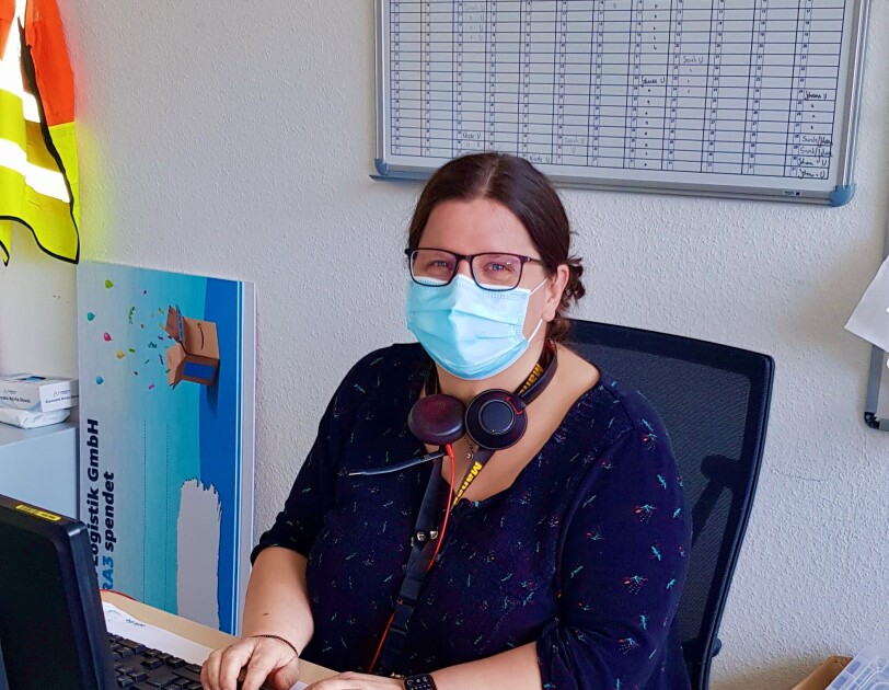 Silvana mit Maske am Schreibtisch.