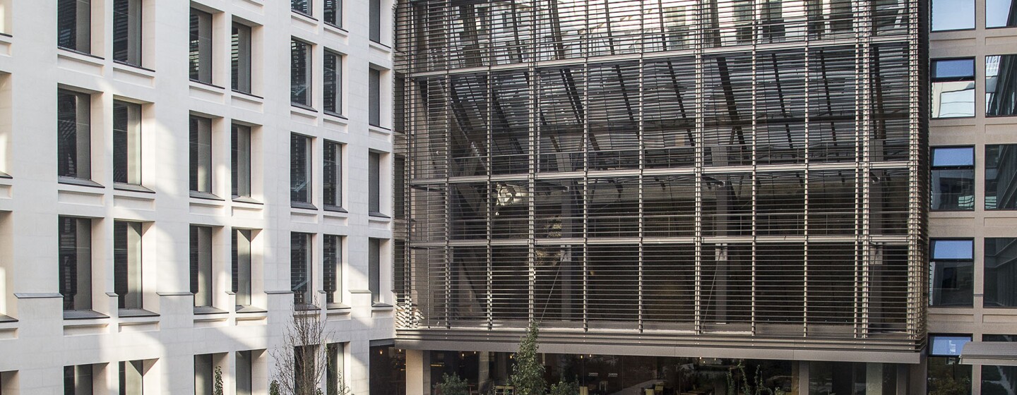 Patio interior de la oficina corporativa en Madrid. El patio es ajardinado y tiene bancos.