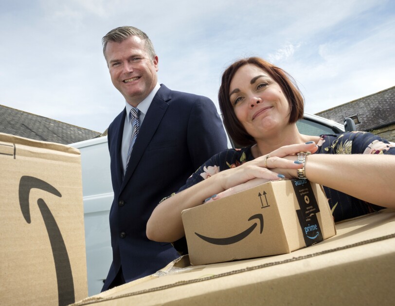 James and Rebecca, owners of JMHC Logistics, standing behind Amazon boxes.