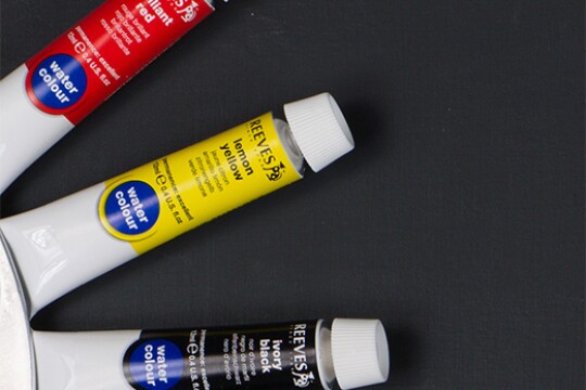 Three tubes of paint are arranged in a radial pattern. The top tube is labeled "brilliant red." The middle is "lemon yellow." The bottom is "ivory black."