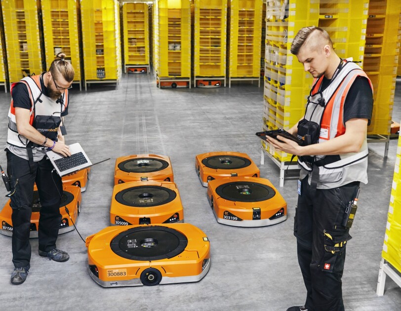Dwóch pracowników Amazon z robotami w centrum logistyki