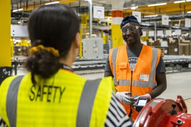 Eine Amazon Safety Mitarbeiterin im Gespräch mit einem Kollegen.