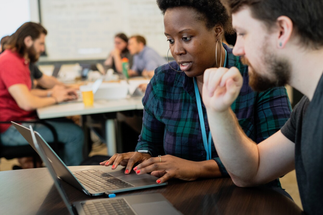 A woman and a man work on laptop computers.