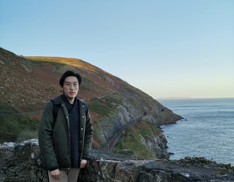 Fangbo Li standing in front of a coastal view