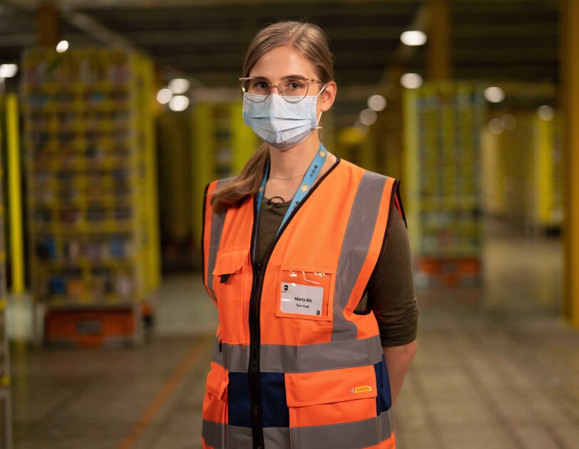 Amazon employee wearing orange high res vest and looking directly at the camera