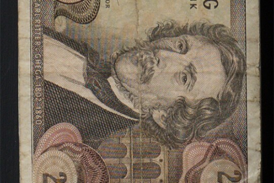 Detail of a piece of old Austrian paper currency. The image includes the number 20 at the corners of the bank note as well as a well as a portrait of a man with a mustache. A label beneath the portrait says "Carl Ritter v. Ghegha 1802 - 1860."