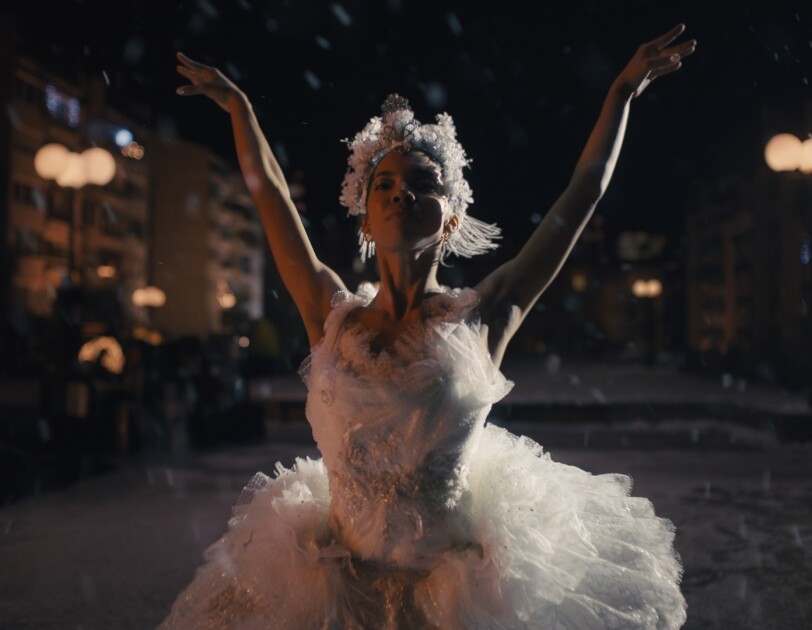 Ballerina dressed in white feathers and arms in the air