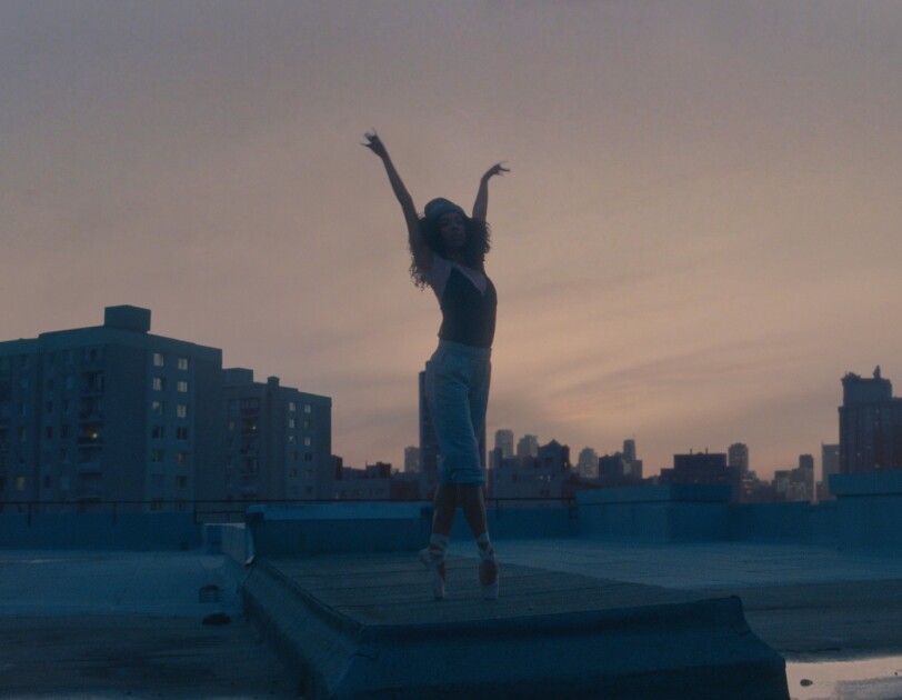 Ballerina stood on top of a rooftop with arms in air