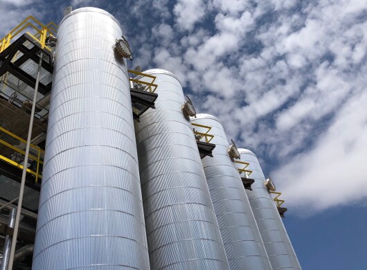 Four metal cylindrical structures shown against a blue sky with clouds.