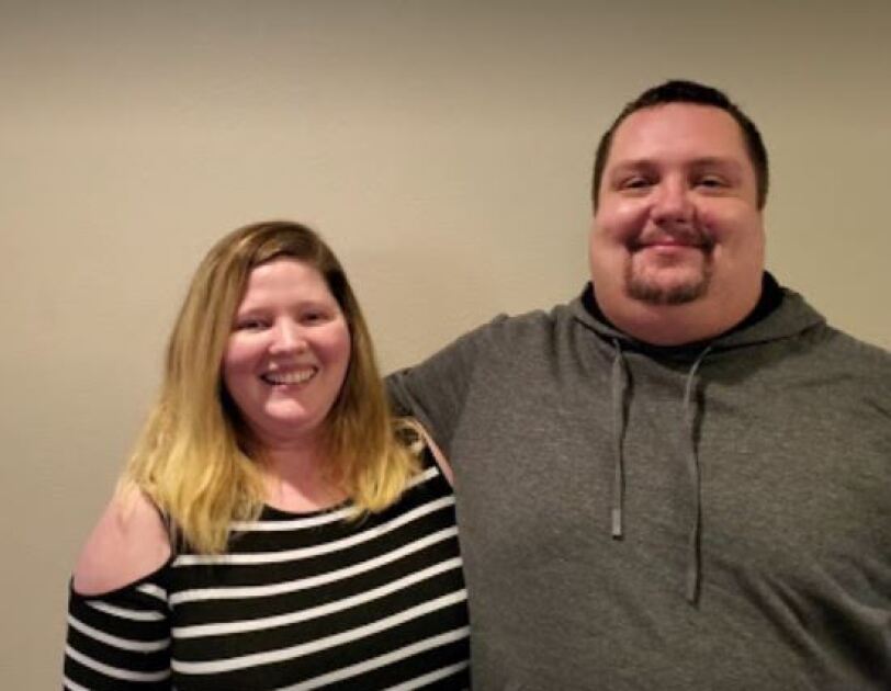 A woman and man stand together, smiles on their faces.