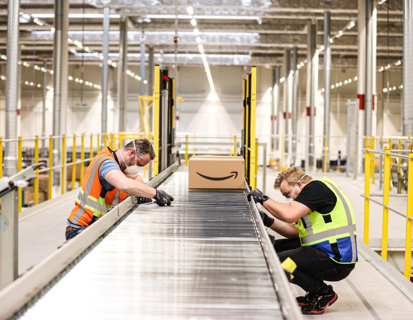 Two engineers assembling a track with Amazon package in background.