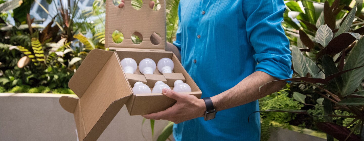 A man stands in the Spheres holding a box full of lightbulbs as part of a packaging test.