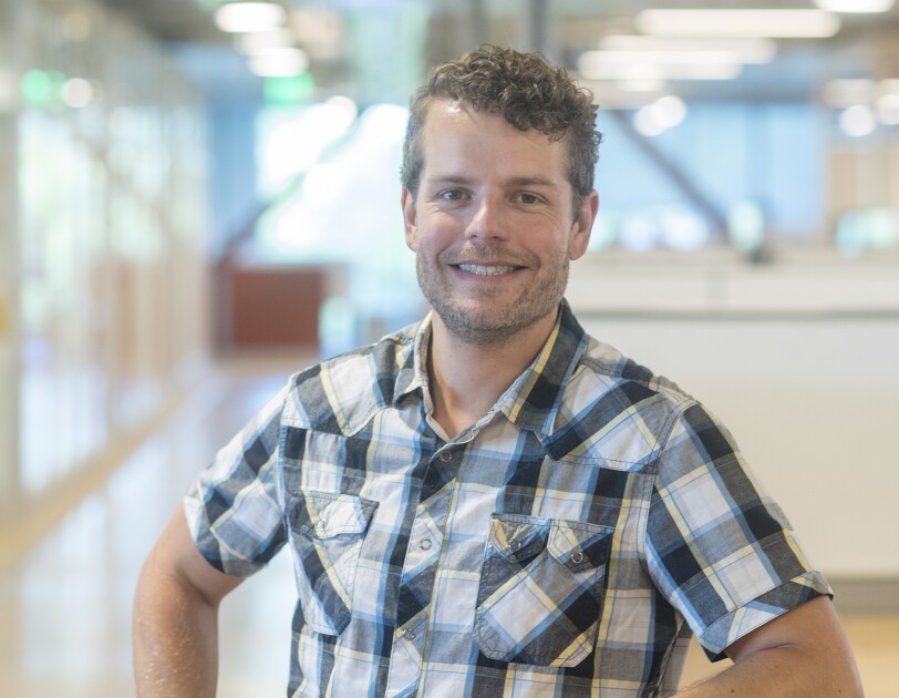 A man wearing a plaid shirt, smiling at the camera.