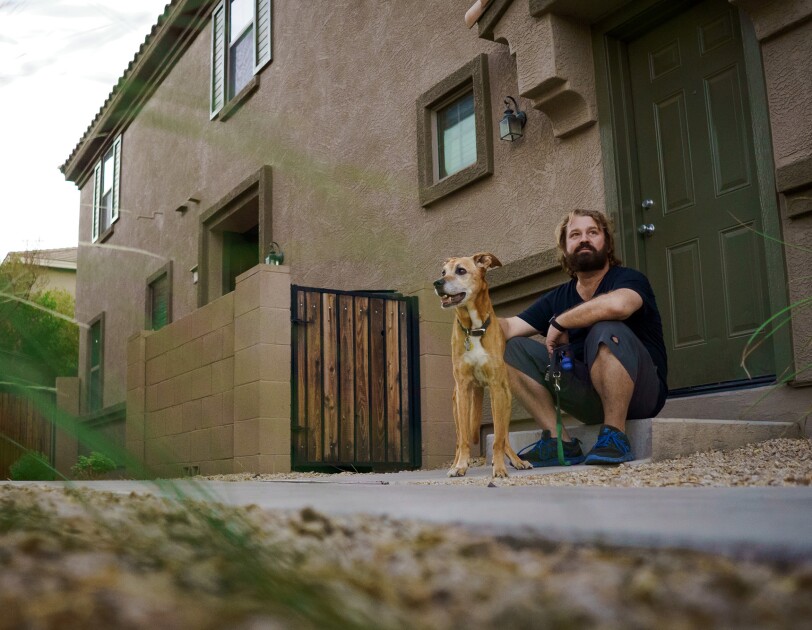 A dog and a man sitting on the doorstep of a home.