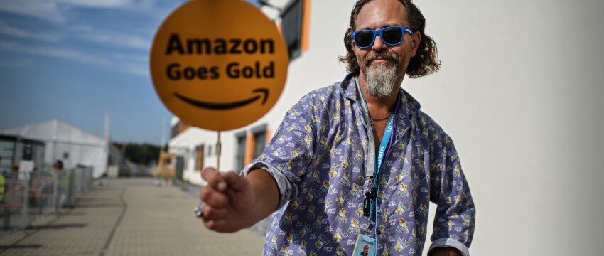 Amazon Mitarbeiter im Schlafanzug mit Amazon Goes Gold Schild