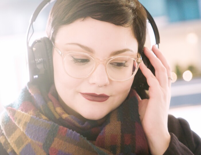 Ritratto di Giulia Massari, Marketing Manager Audible, mentre indossa delle cuffie e ascolta della musica.