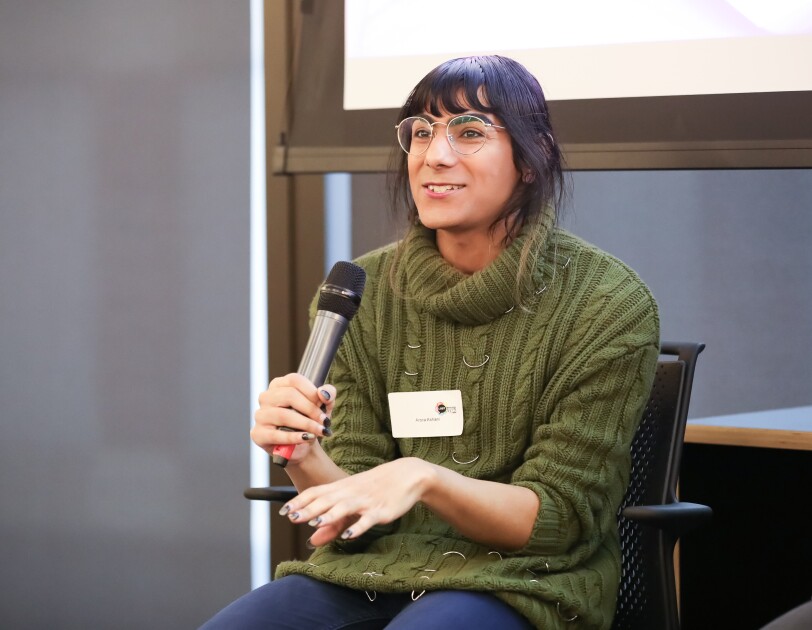 Arora Ashani is a developer for YOOX Net-a-Porter and co-founder of Non-Binary in Tech, holding a mic and giving a talk at the LGBT Leaders in STEM event.