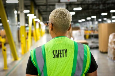 A person wearing a safety vest in a warehouse.