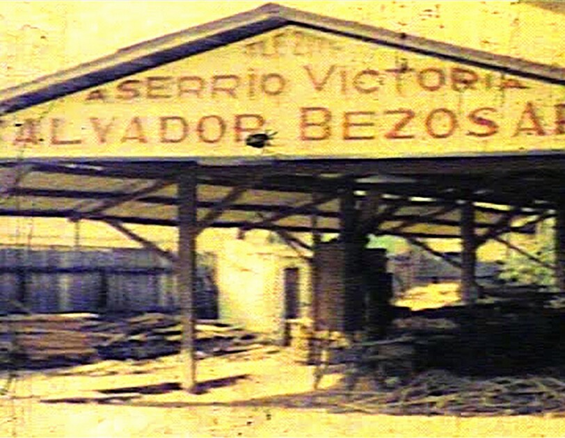 Vintage image of a lumber mill. The painted sign on the building includes the family name "Bezos."