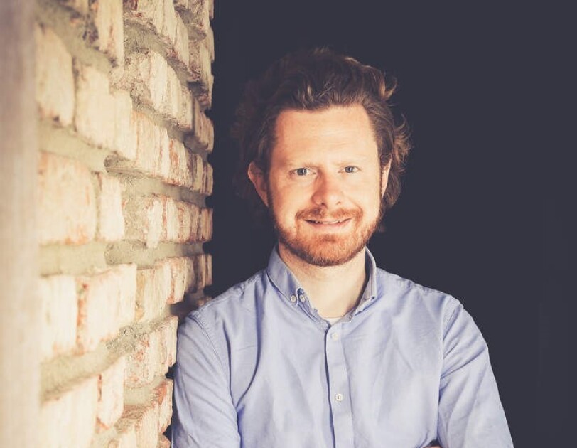 Jan Korves, Senior Manager Consumables bei Amazon. Er trägt ein hellblaues Hemd und lehnt an einer Steinmauer.