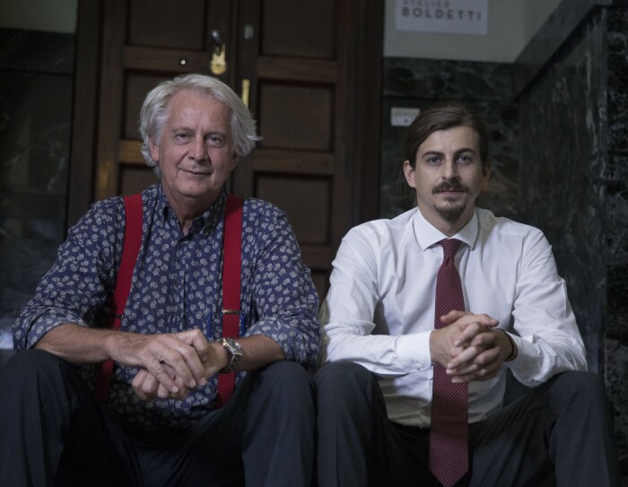 Due uomini sono seduti fianco a fianco su uno scalino all'ingresso di un palazzo. A sinistra Giorgio Boldetti, e accanto a lui Giulio Boldetti, 32 anni, entrambi proprietari dell’Atelier Boldetti di Torino.