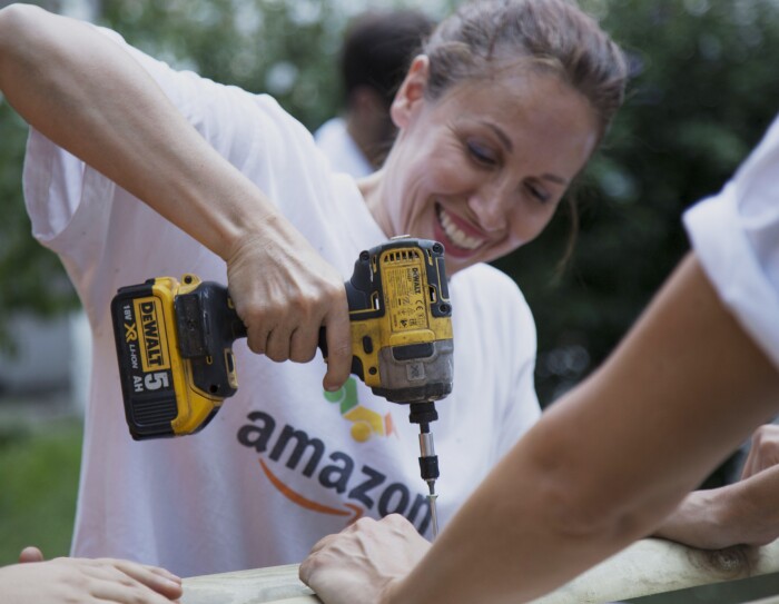 Volontaria di Amazon sorride in primo piano mentre regge un trapano durante i lavori alla Scuola Media Leonardo da Vinci di Affori, nella periferia di Milano.