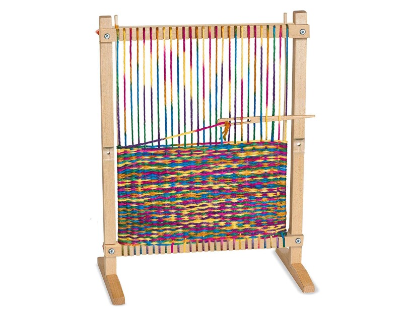 Wooden weaving loom, with loomed article partially completed with rainbow-colored threads.