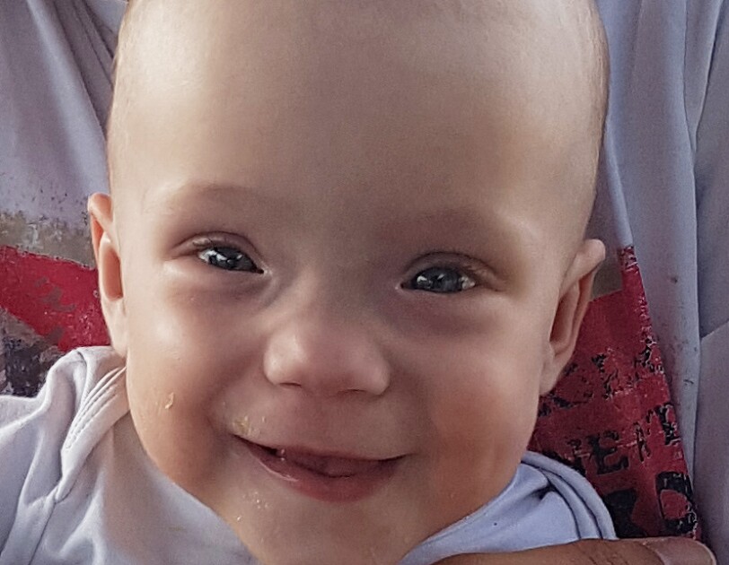 Lena ist ein kleines Baby. Sie hat große Augen und lacht in die Kamera.