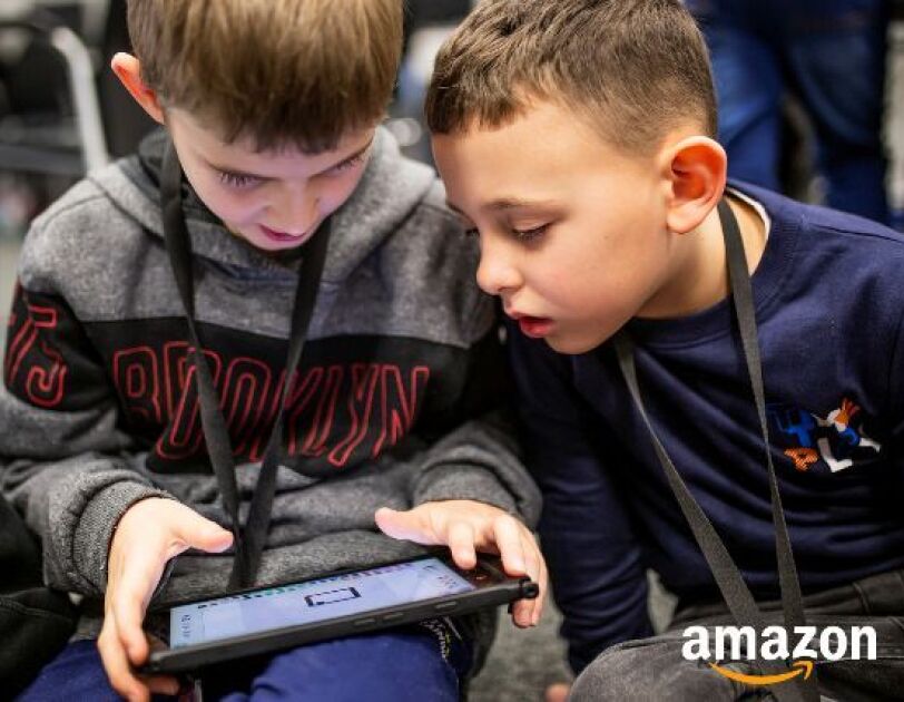 Two young boys play on a tablet device.