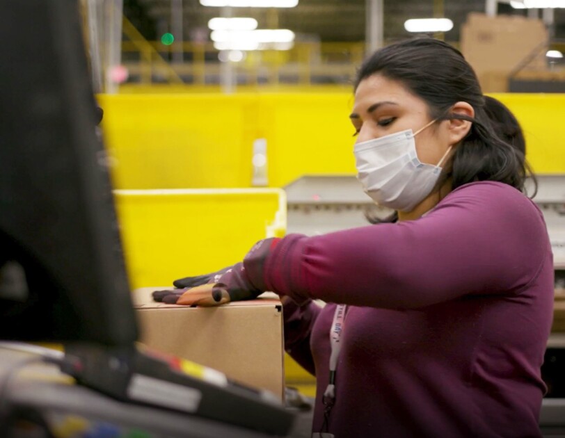 Amazon employee performing work duties while wearing a mask, during COVID-19 pandemic.