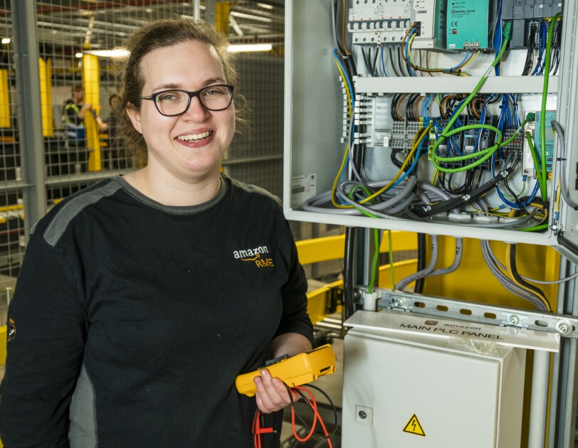 Nicola Elliott, automation engineering apprentice standing in front of an electrical unit.